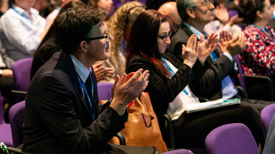 A row of people at a property managers industry event clapping