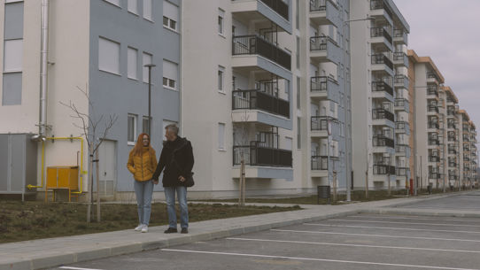 Two people holding hands next to an apartment complex